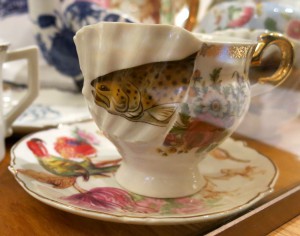 tea cup and saucer with a perch and some parrots